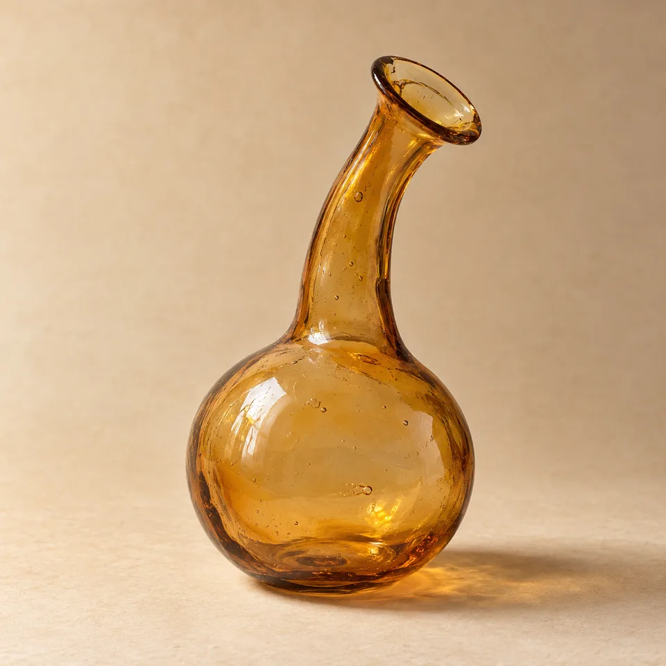 Complete amber glass vessel with rounded bulb and a narrow bent open neck