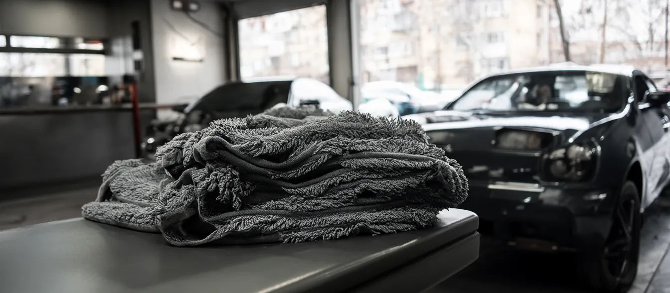 A dark sedan in a detailing bay, with soft microfiber towels on a bench.