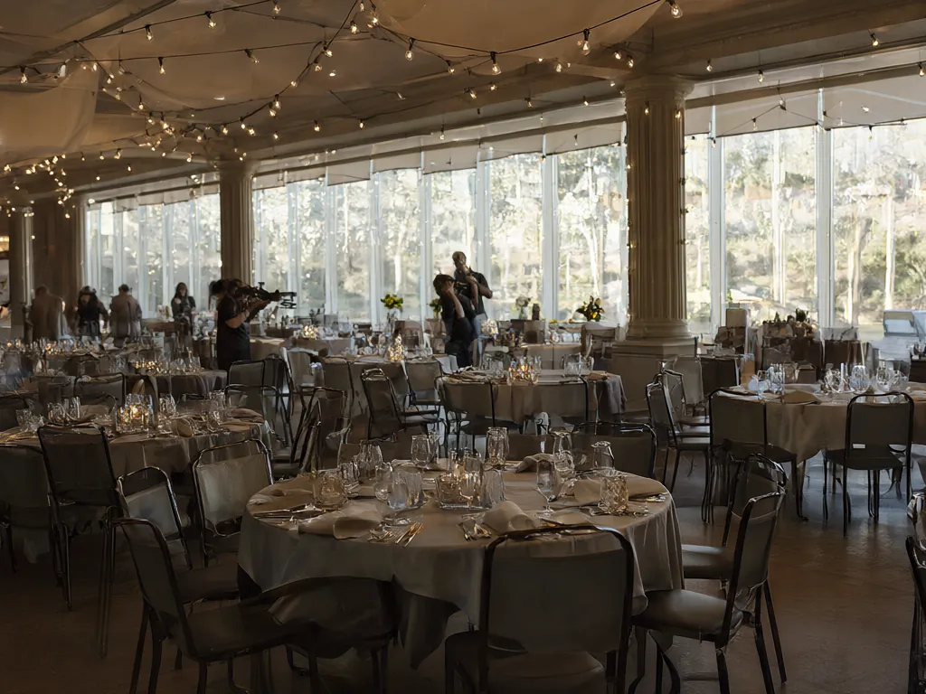 A bright event room set with round tables and soft string lights.
