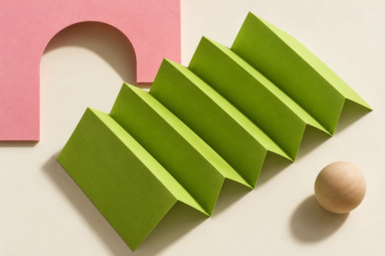 Illustrative cut-paper collage of lime folded leaves and a pink arch beside a wooden sphere