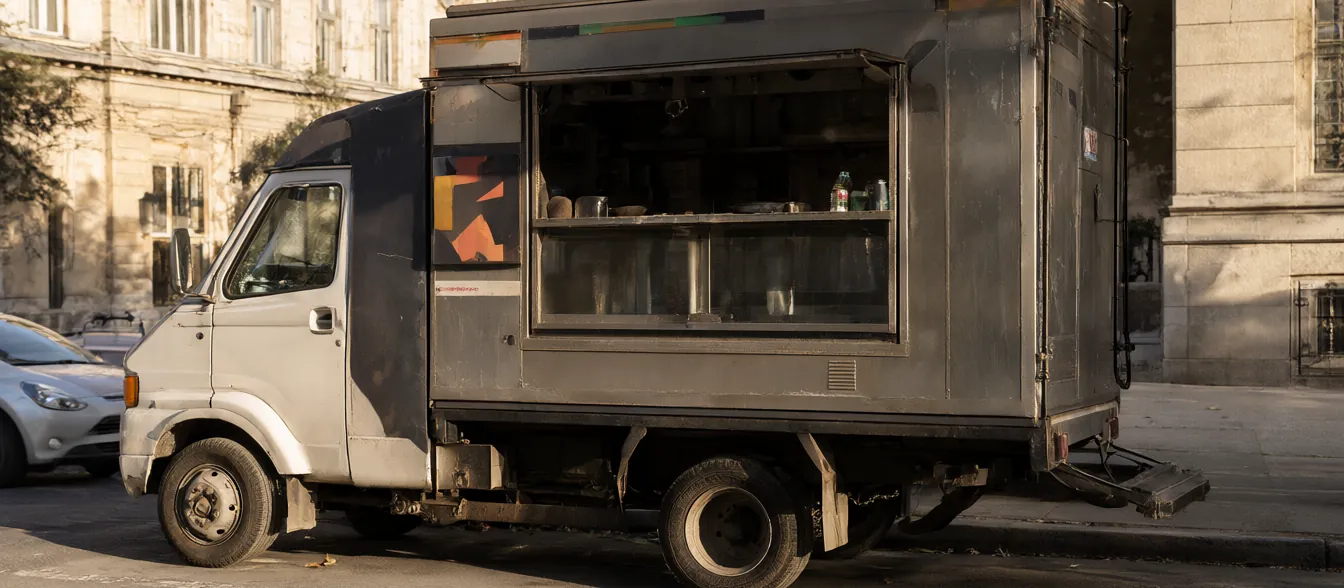 The food truck with its serving window open at a curbside stop.