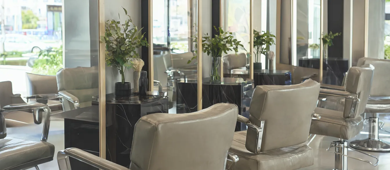 A bright salon with styling chairs in front of large mirrors.