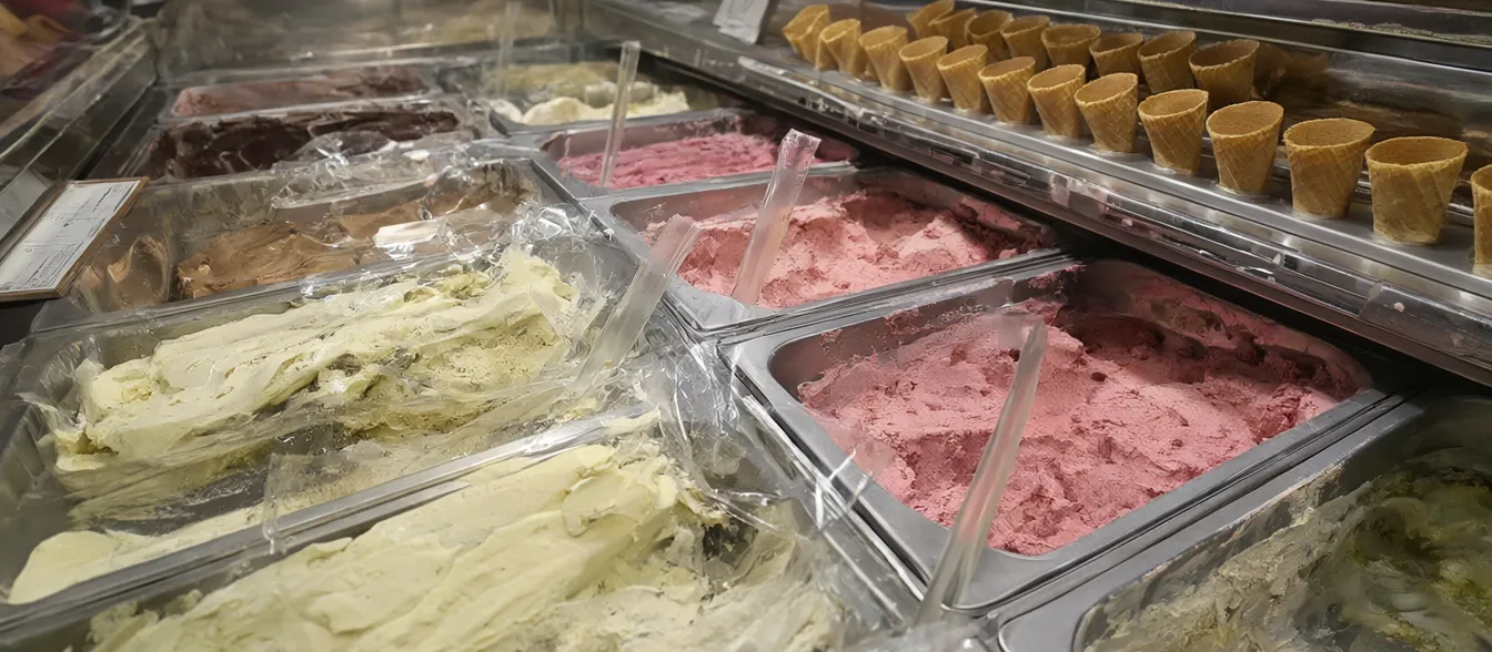 Scoops of ice cream in waffle cones on a dessert counter.