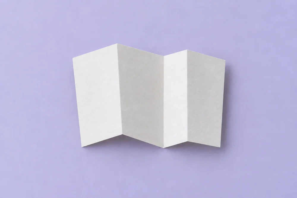 Generated overhead view of a separated white folded sheet on pale lilac.
