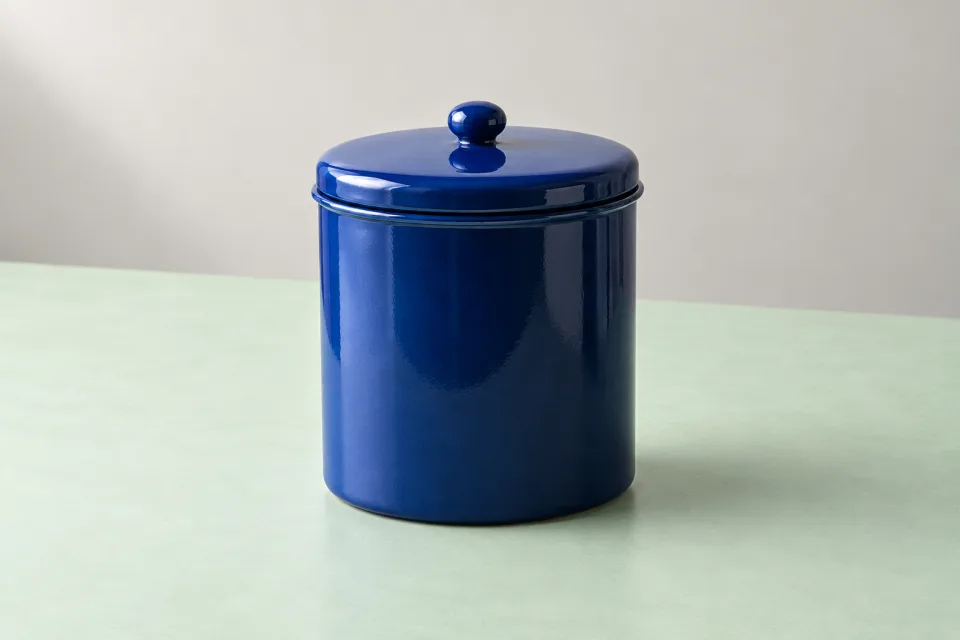 Complete cobalt-blue enamel-style cylindrical canister with fitted lid and round knob on a mint studio surface