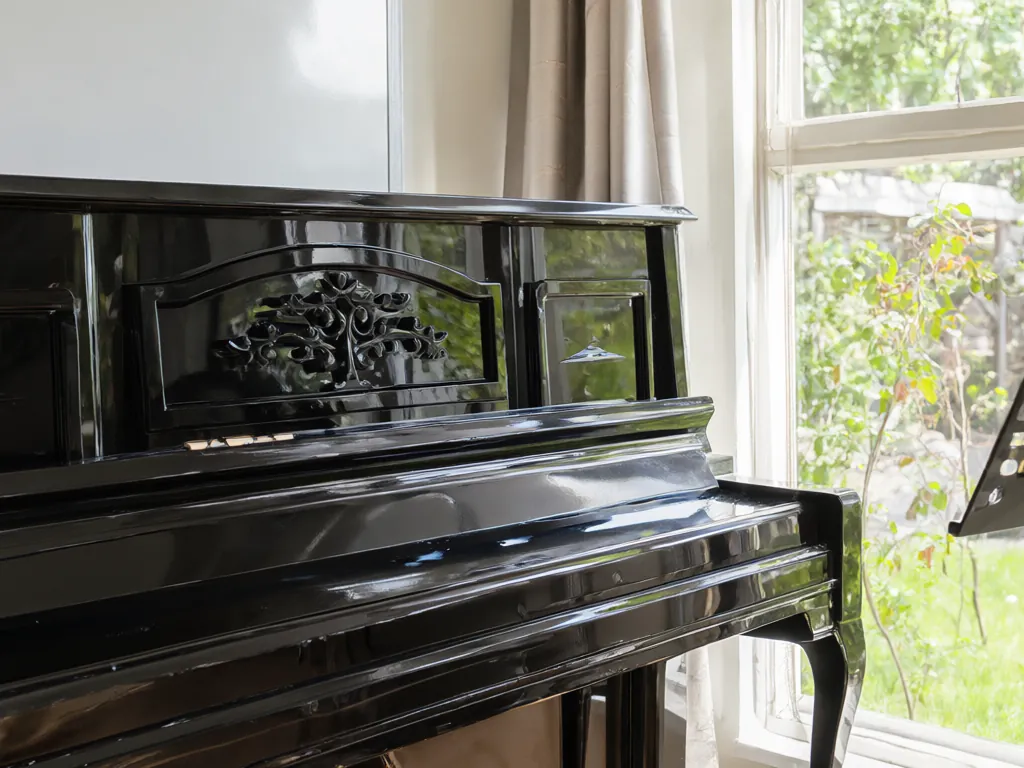 An upright piano by a window in a bright teaching room.