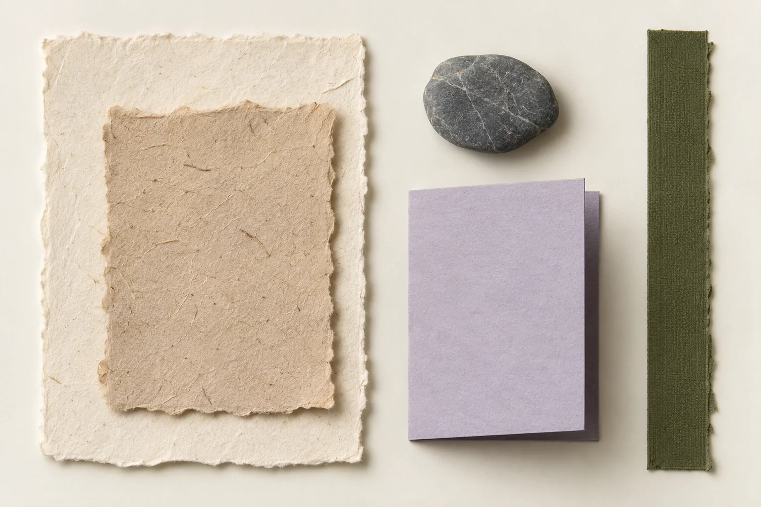 Illustrative scanned archive of neutral paper swatches, a lavender folded card, an olive strip and a small stone