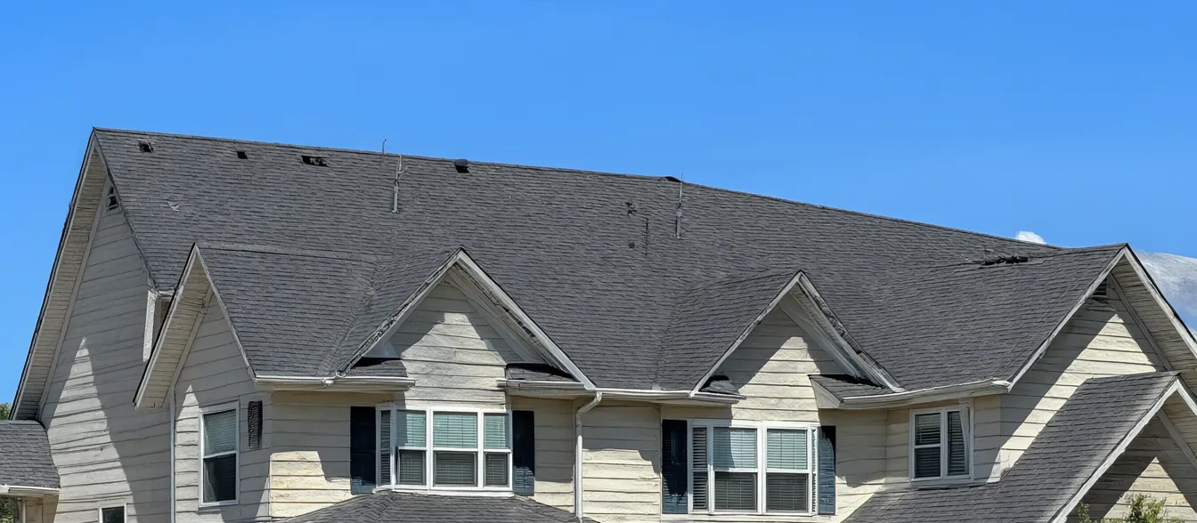 A two-story house with a new dark shingle roof.