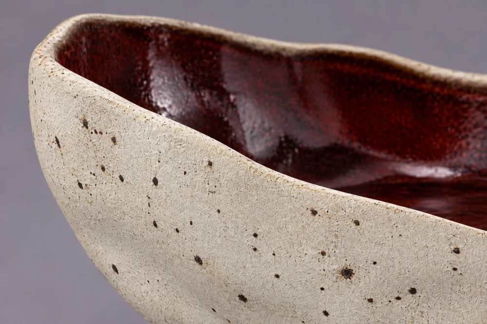 Illustrative detail: the matte clay rim turns into the oxblood glazed interior.
