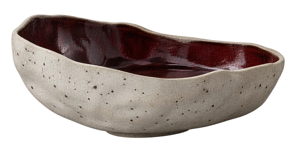 Illustrative hand-shaped low vessel with a mineral-speckled pale body, uneven rim and oxblood interior.